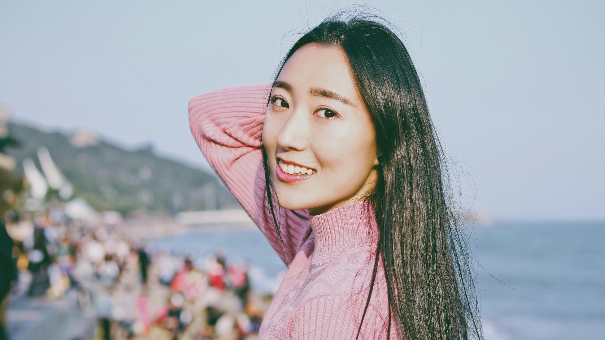 Portrait of a smiling woman by the sea in Xiamen, capturing her joyful expression and serene surroundings.